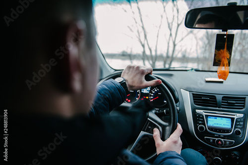 A young man driving an auto. A man sits inside a car in the driver's seat © bo.kvk
