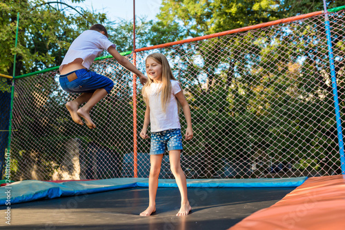 Boy and girl jump on the trampoline in the park © illustrissima