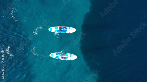 Aerial drone bird's eye view of 2 men exercising sup board in turquoise tropical clear waters