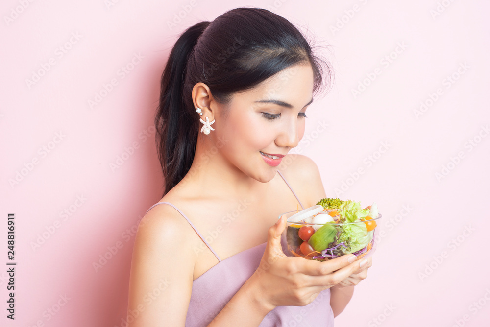 Beautiful Healthy young woman eating salad on pink background Beautiful Healthy young woman eating salad on pink background