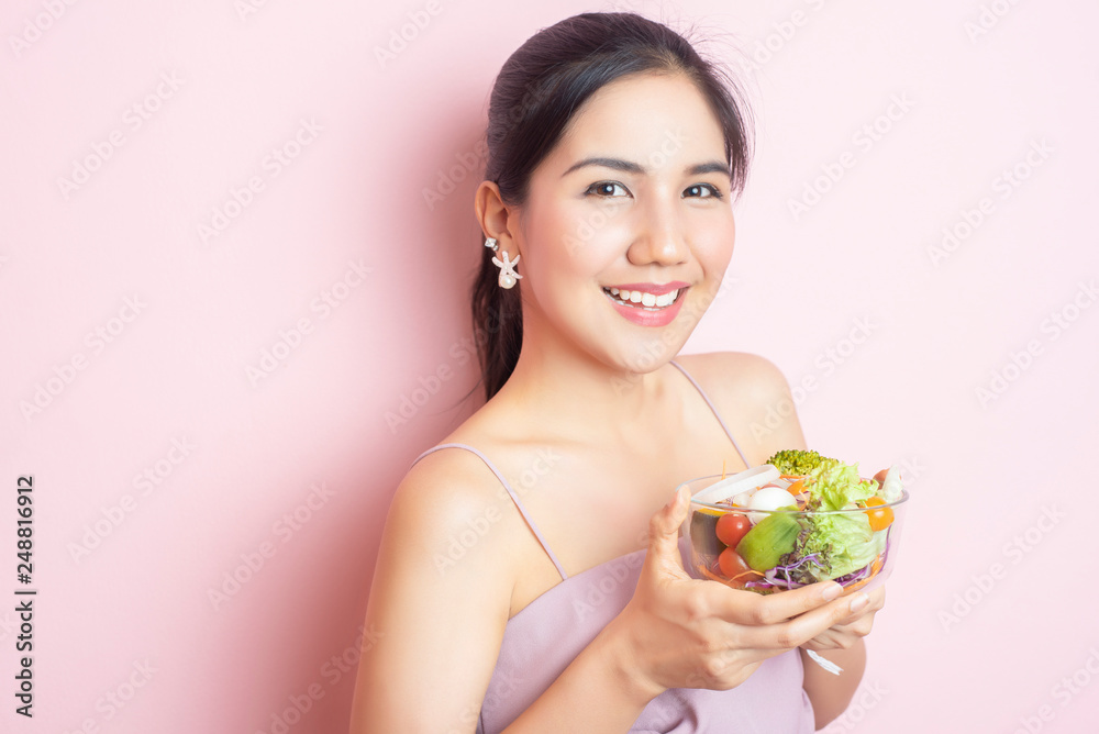 Beautiful Healthy young woman eating salad on pink background Beautiful Healthy young woman eating salad on pink background