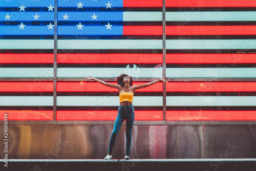 Woman with arms outstretched in front of American Flag on Times Square