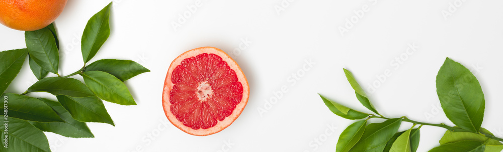 fresh, juicy grapefruit with green twigs lying on a white background fresh, juicy grapefruit with green twigs lying on a white background