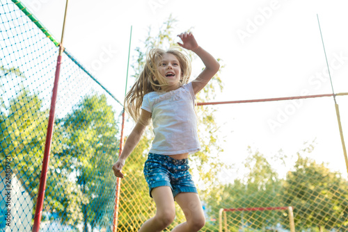 Happy funny girl jumping on trampoline