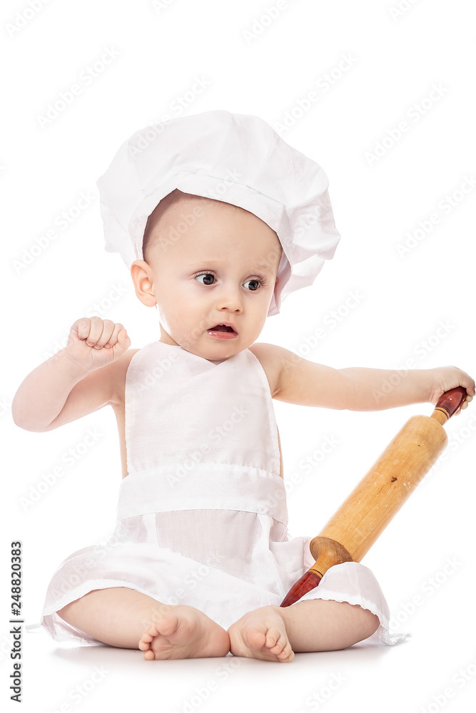 Infant cook baby in the cook costume and chef hat with dough rolling pin, isolated on a white background Infant cook baby in the cook costume and chef hat with dough rolling pin, isolated on a white background