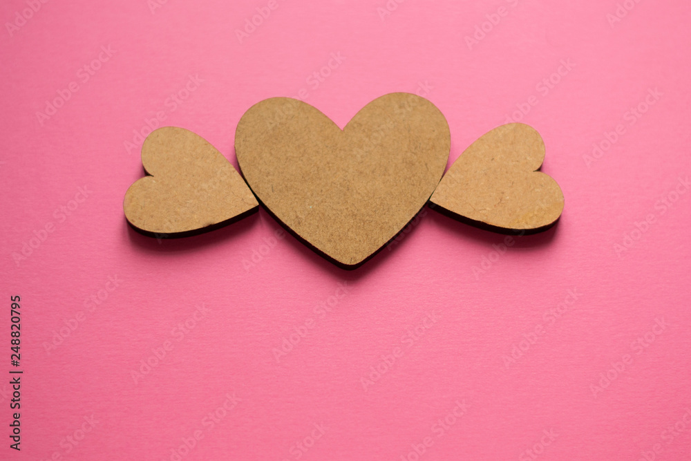 Light wooden heart with wings on pink background with copy space. Spring composition flat lay from top view.