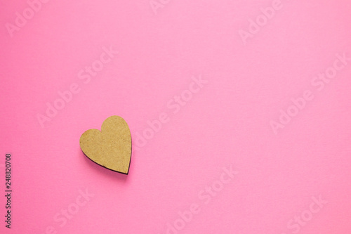 One wooden heart on pink background with copy space for text. Concept of love, Valentine's day, international women's day, wedding, greeting card, anniversary.