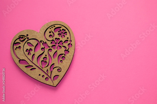 Beautiful textured poker-drawing wooden heart on pink background with copyspace as a symbol of love, Valentine's day, greeting card, wedding, anniversary, international women's day.