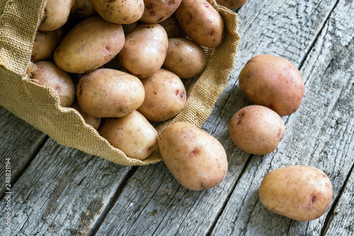 Raw potatoes fell out of the bag on wooden boards