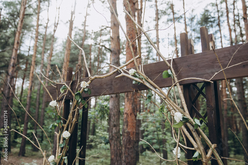 in the forest among the trees there is an arch for the wedding ceremony, decorated with branches and flowers