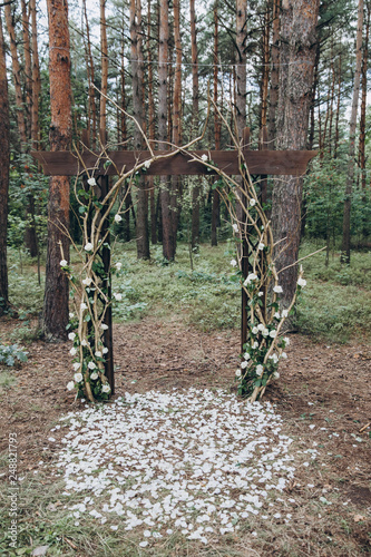 Fototapeta Naklejka Na Ścianę i Meble -  in the forest among the trees there is an arch for the wedding ceremony, decorated with branches and flowers