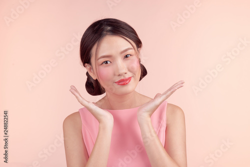 Fashion portrait of a beautiful young woman in a pretty dress over pink background