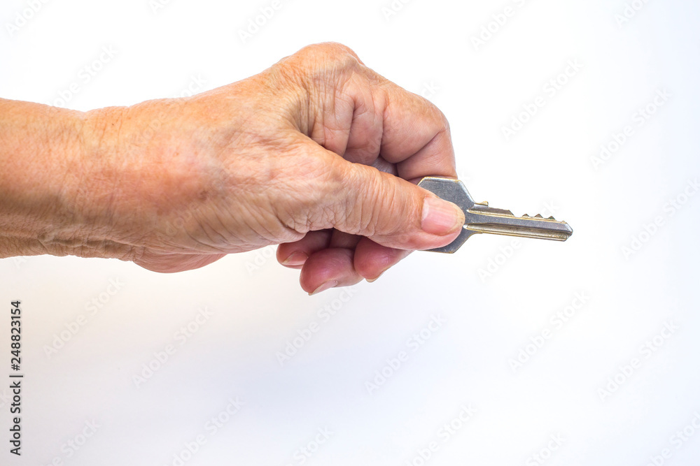 Senior woman's left hand holding key isolated on white background Senior woman's left hand holding key isolated on white background