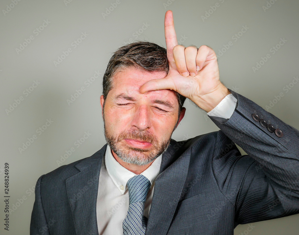unshaven sad and ashamed businessman crying doing loser sign with hand ...
