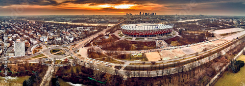 Beautiful panoramic aerial drone view to panorama of Warsaw modern City with skyscraper and The PGE Narodowy National Stadium (Polish: Stadion Narodowy) against the background of a dramatic sunset