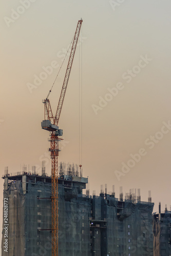 Foto Luffing jib tower crane at condominium construction site over steel framework among high rise building