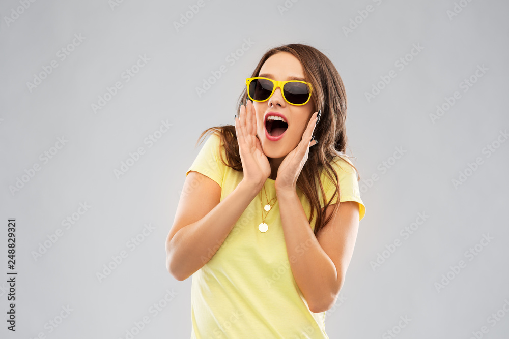 summer, accessory and people concept - amazed young woman or teenage girl in yellow t-shirt and sunglasses over grey background summer, accessory and people concept - amazed young woman or teenage girl in yellow t-shirt and sunglasses over grey background