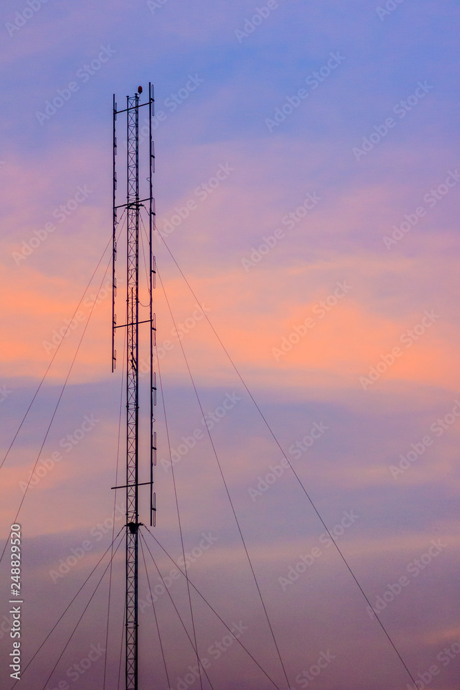 Cellular transmitter, folded dipole radio antenna for telecommunications with colorful sky background. Silhouette amateur radio antenna tower in dramatic sky background. Cellular transmitter, folded dipole radio antenna for telecommunications with colorful sky background. Silhouette amateur radio antenna tower in dramatic sky background.