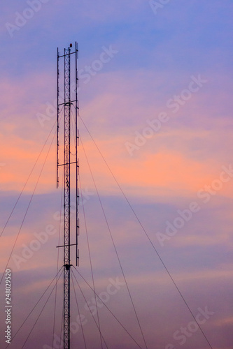 Cellular transmitter, folded dipole radio antenna for telecommunications with colorful sky background. Silhouette amateur radio antenna tower in dramatic sky background.