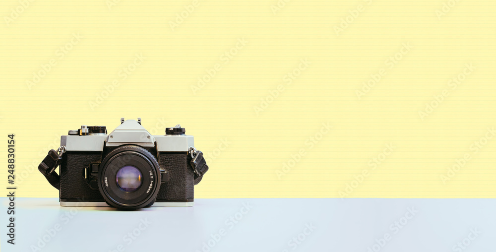 Vintage photography camera on yellow colored background, retro
