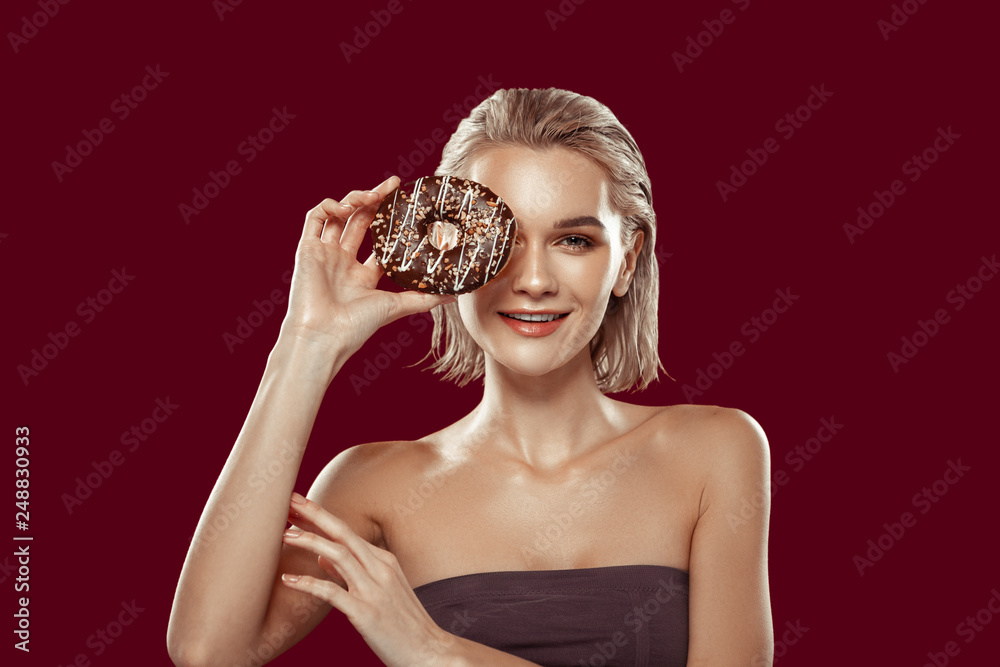 Slim photo model holding chocolate doughnut while posing