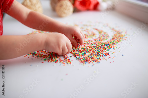 Baby hands in sugar topping. Baby drawing. Baby fingers with candies. Easter sugar topping. © Маргарита Щипкова