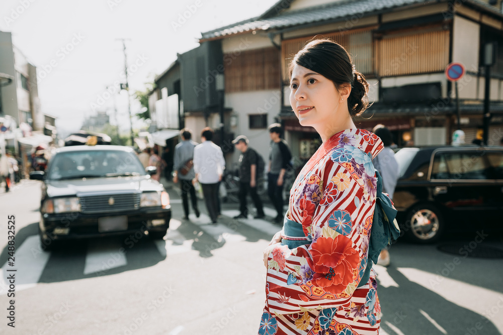 elegant asian lady in colorful kimono cloth walking on road with cars busy traffic driving. beautiful japanese woman in traditional cloth happy look at sunset on street. local men on zebra crossing.