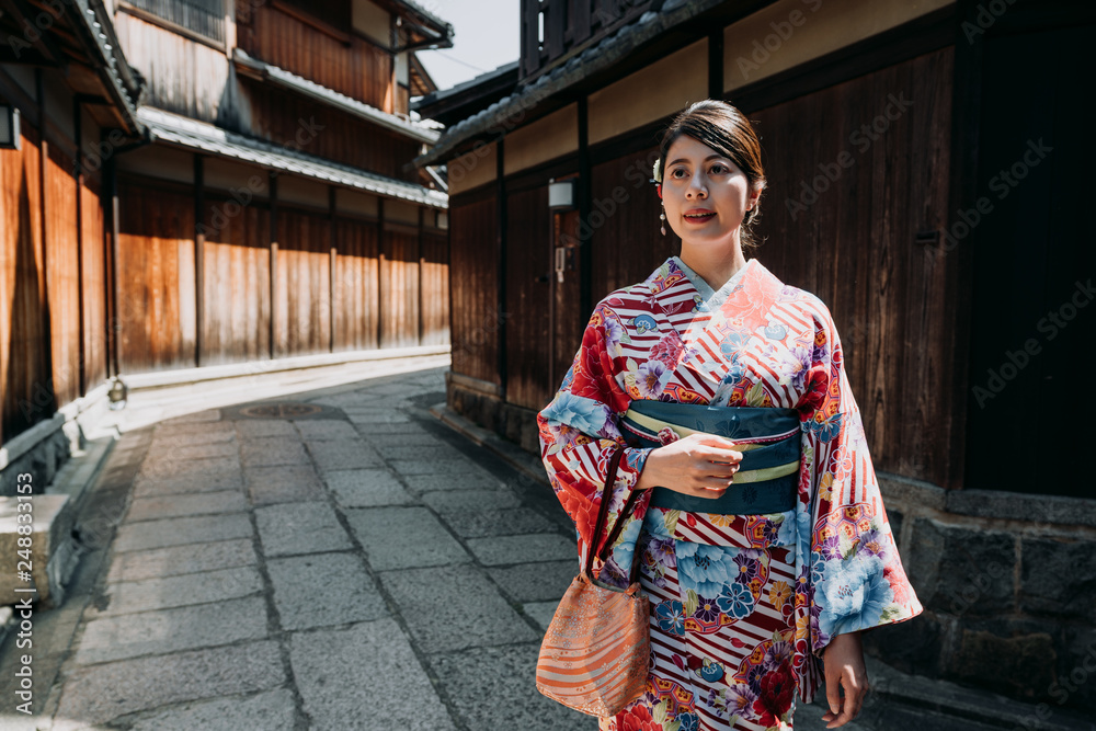 japanese local woman in floral kimono dress lifestyle in wooden wall ishibe alley. young girl in traditional cloth walking on stone road surrounding by old historical wood house looking up blue sky. japanese local woman in floral kimono dress lifestyle in wooden wall ishibe alley. young girl in traditional cloth walking on stone road surrounding by old historical wood house looking up blue sky.