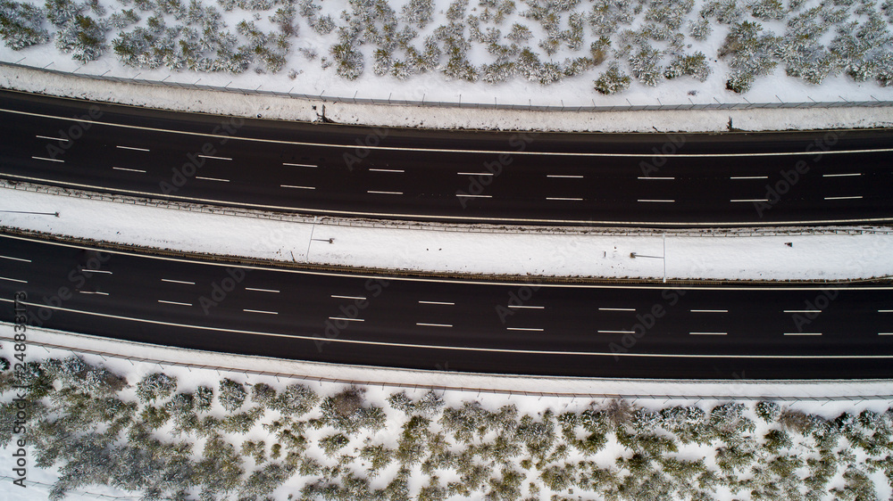 Aerial view of highway in winter time. Aerial top view of highway with low traffic on snowy winter day Aerial view of highway in winter time. Aerial top view of highway with low traffic on snowy winter day