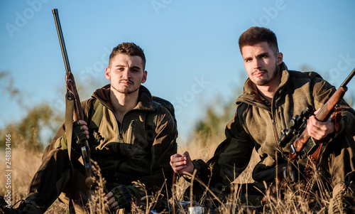 Hunters with rifles relaxing in nature environment. Hunters satisfied with catch drink warming beverage. Hunters friends enjoy leisure. Rest for real men concept. Hunting with friends hobby leisure