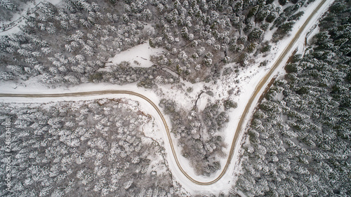 Aerial view of a road in idyllic winter landscape. Country road going through the beautiful snow covered landscapes.  © yusufozluk