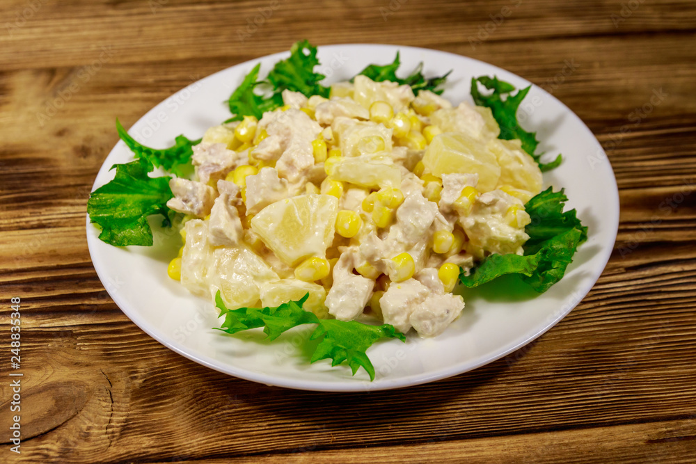 Festive salad with chicken breast, sweet corn, canned pineapple and mayonnaise on wooden table Festive salad with chicken breast, sweet corn, canned pineapple and mayonnaise on wooden table