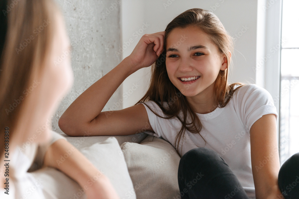 Two cheerful girls talking while sitting at home Two cheerful girls talking while sitting at home