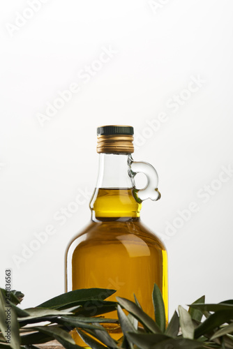 bottle of oil and olive tree leaves isolated on grey