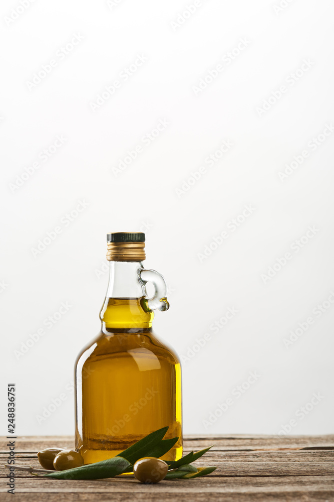 bottle of with olive tree leaves and olives  isolated on grey