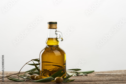 oil bottle with olive tree leaves and olives isolated on grey