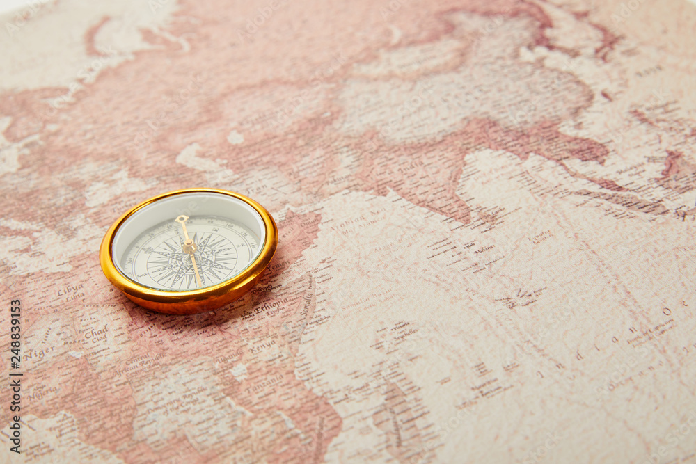 golden compass on vintage world map