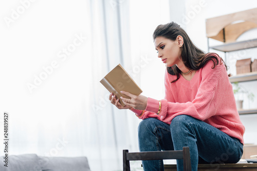 female indian student reading book at home