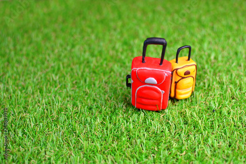 Toy little baggage on green artificial grass lawn