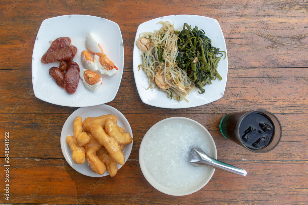 Thai rice gruel breakfast set served on wooden table.