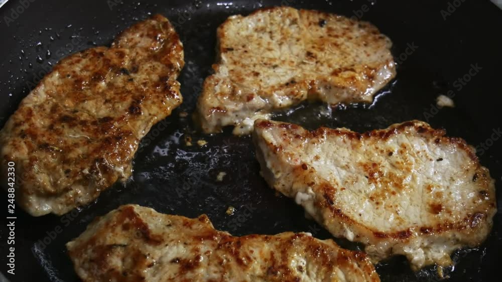 Close-up of pork chops are fried in a frying pan. Pork chops in a skillet. Close-up of pork chops are fried in a frying pan. Pork chops in a skillet.