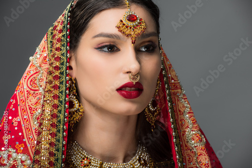 attractive indian woman posing in traditional sari and bindi, isolated on grey