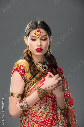 attractive indian woman in traditional clothing and accessories, isolated on grey