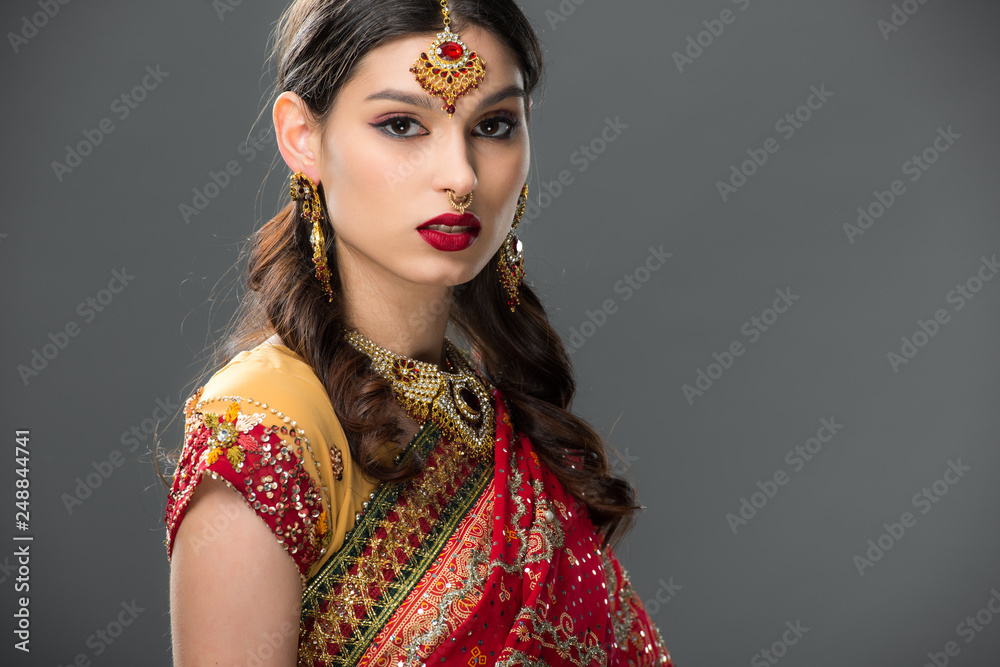 Fototapeta premium beautiful indian woman in sari and accessories, isolated on grey