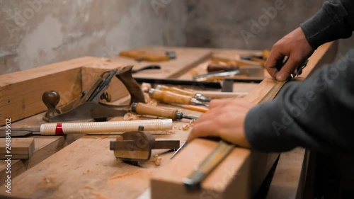 carpenter marks the workpiece with a tape measure and a pencil