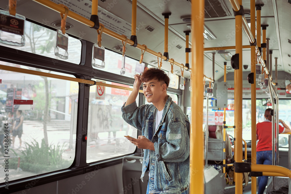 handsome young man in a blue denim jacket using smartphone in bus
