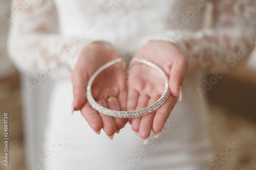 hands of the bride with delicate  jewelry. the girl holds the silver diadem on her hand. morning of the bride. wedding day. wedding concept.