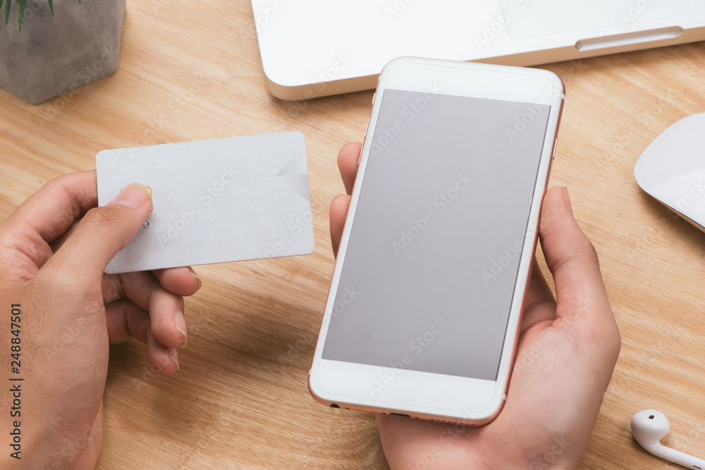 Hands holding credit card, smart phone and using laptop. Online shopping concept-vintage tone and flare filtered Hands holding credit card, smart phone and using laptop. Online shopping concept-vintage tone and flare filtered