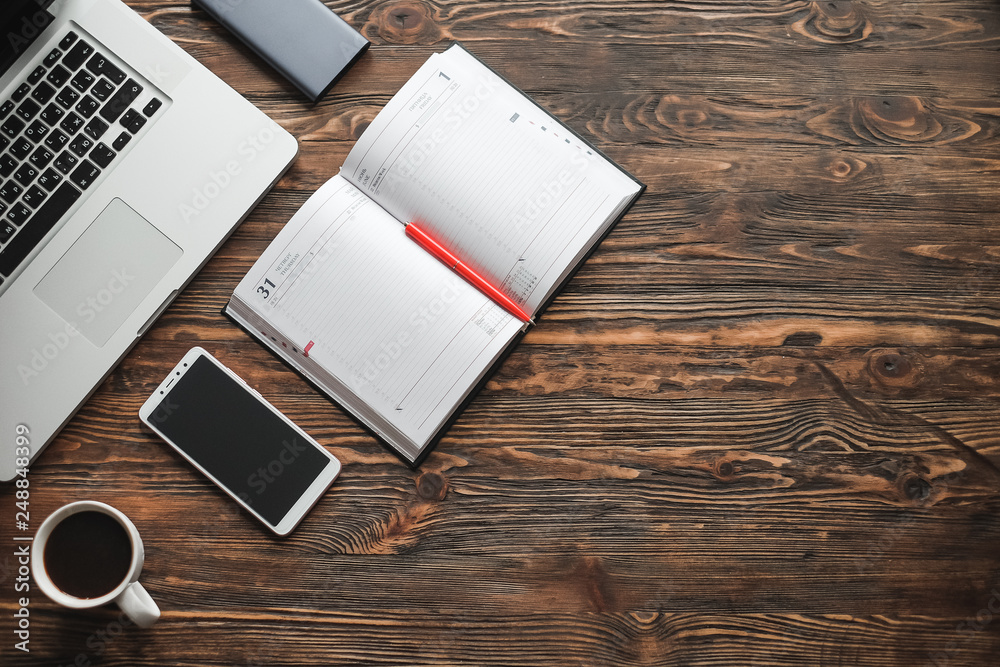 Top view of accessories on the workplace mobile phone, laptop, diary, pencil, coffee, vintage photo camera on wooden office table background. Top view of accessories on the workplace mobile phone, laptop, diary, pencil, coffee, vintage photo camera on wooden office table background.
