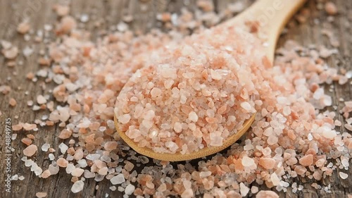Pink Himalayan salt in spoon on wooden background. Healthy spice closeup. Different focal lengths